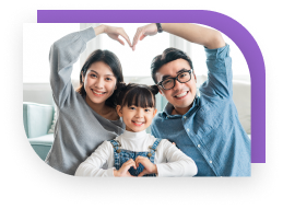 Parents and a child sit together and make heart signs with the hands and arms.