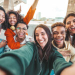 Young adults taking a selfie, all smiling and laughing toward the camera.
