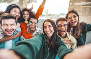 Young adults taking a selfie, all smiling and laughing toward the camera.