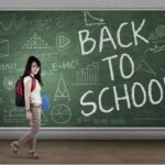 A student standing in front of a chalkboard that says Back to school in large chalked letters