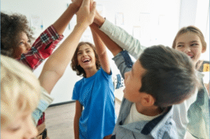 Kids in a circle with one arm in the air bring all their hands together in the middle.