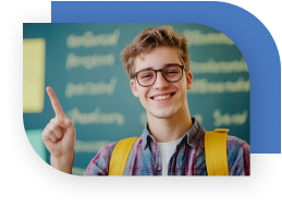 A teen smiles and holds one hand up with his index finger pointing up. He is wearing a backpack and has a chalkboard behind him.